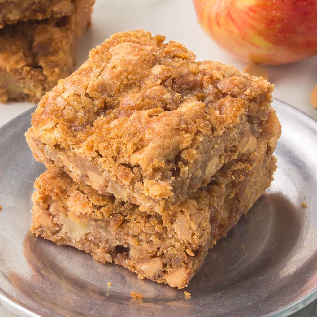 a stack of apple blondies with peanut butter chips on a silver plate.