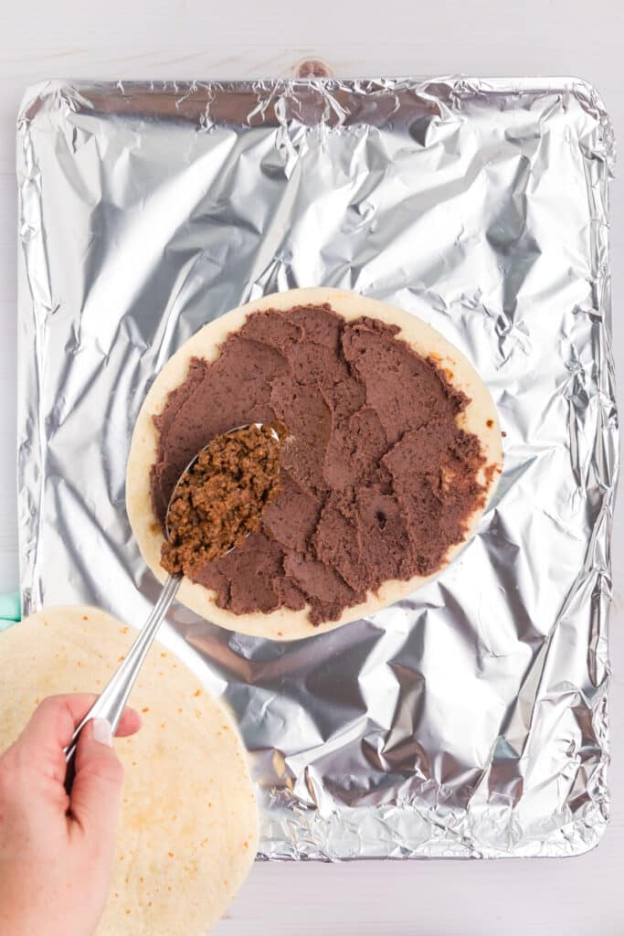 refried black beans spread on a tortilla.