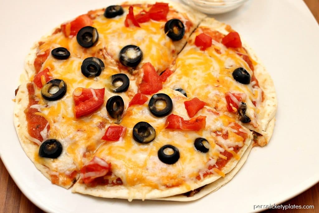 mexican pizza topped with black olives on a white plate