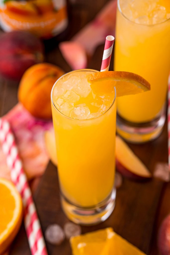 fuzzy navel cocktail in a highball glass with a striped straw