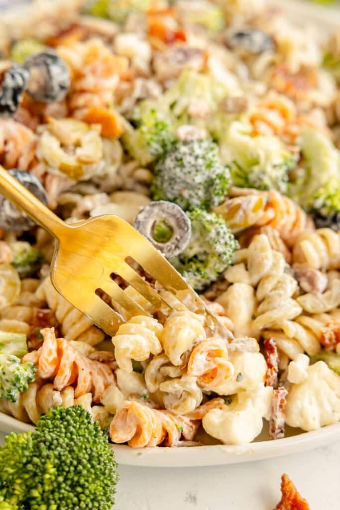 gold fork getting a bite of bacon ranch pasta salad.
