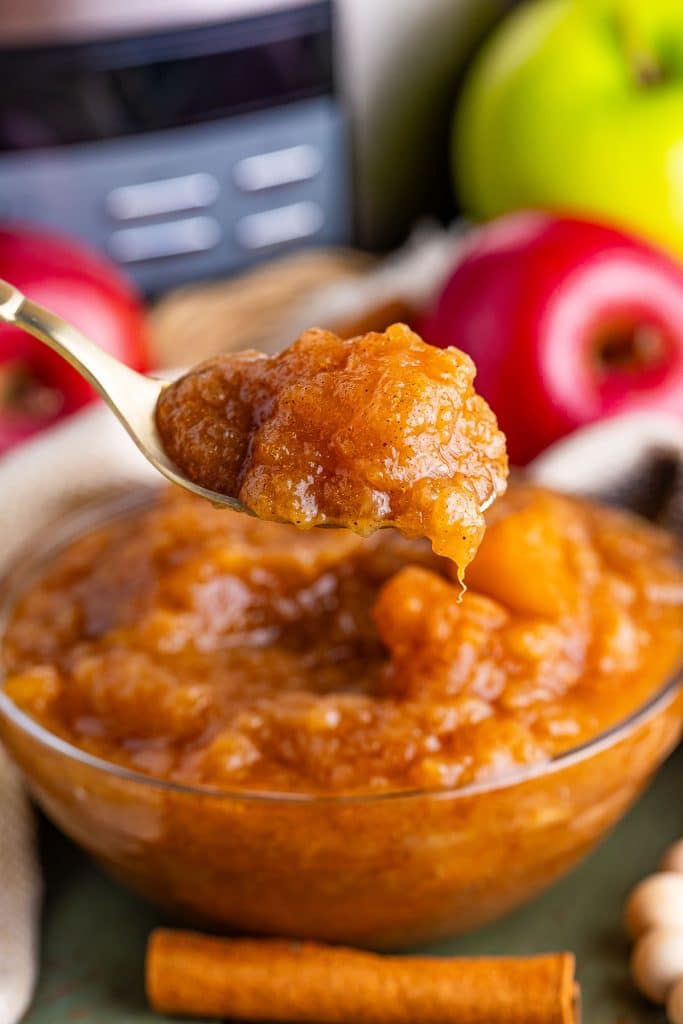 spoon lifting a bite of applesauce from a bowl.