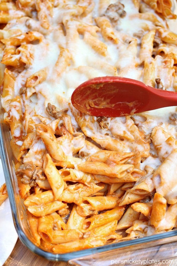 Baked Mostaccioli is a super simple and tasty pasta with a blend of marinara and alfredo sauces. With only five ingredients, it comes together fast and is perfect for an easy dinner! | www.persnicketyplates.com baked mostaccioli with a portion taken out and a red serving spoon