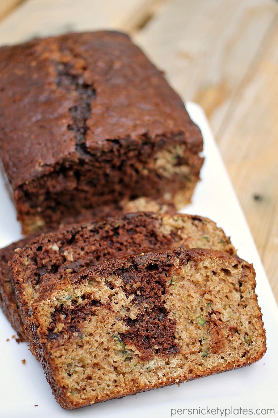 Chocolate Marble Zucchini Bread - give classic zucchini bread an upgrade when you swirl in chocolate batter and mini chocolate chips! | www.persnicketyplates.com chocolate marble zucchini bread sliced on a white platter