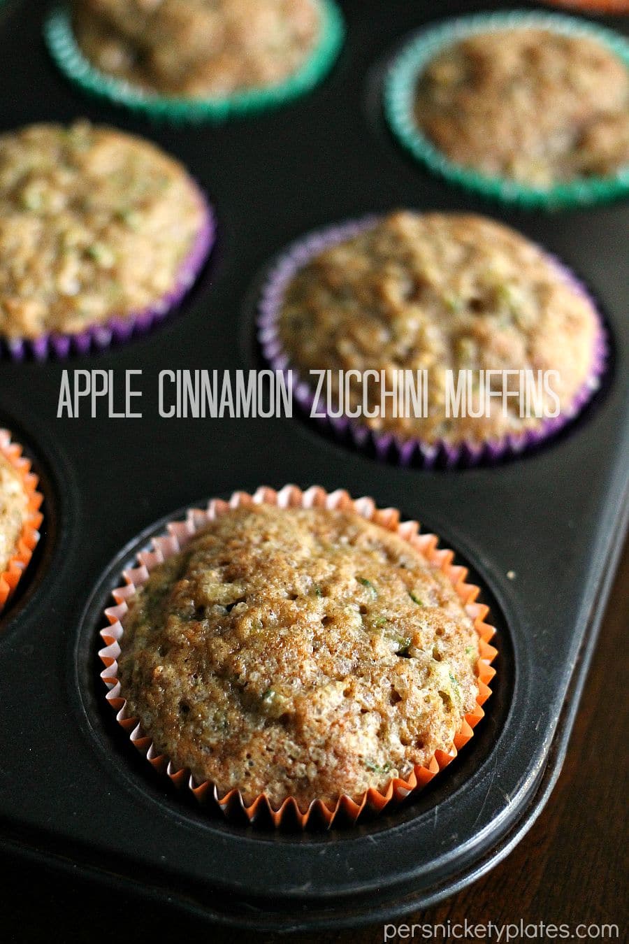 apple zucchini muffins in muffin tray pan of muffins with text overlay reading "apple cinnamon zucchini muffins".
