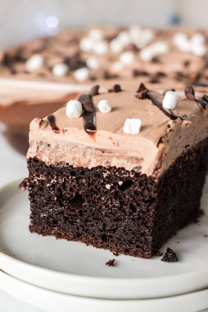 slice of chocolate poke cake topped with mini marshmallows.