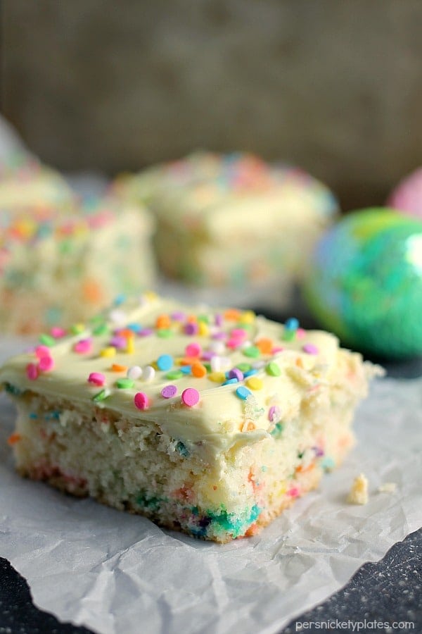 cream cheese funfetti bar topped with sprinkles on parchment paper Cream Cheese Funfetti Bars are simple, semi-homemade treats that are perfect to kick off spring baking. Start with a box funfetti cake mix and add cream cheese to make these fun and delicious bars! | www.persnicketyplates.com