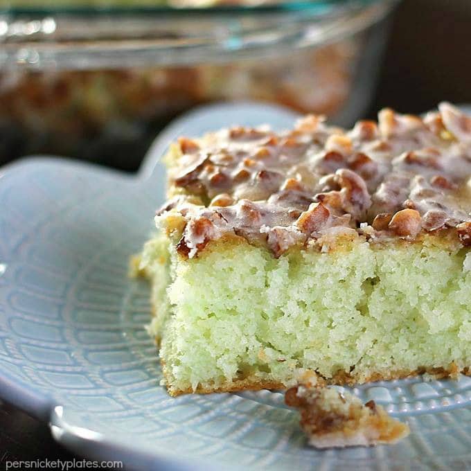 Pistachio Cake starts with a cake mix so it’s super easy and always a crowd pleaser. I’ve never made this cake without being asked for the recipe! Topped with pecans and filled with delicious pistachio pudding, this pistachio pudding cake is simple yet irresistible! | www.persnicketyplates.com