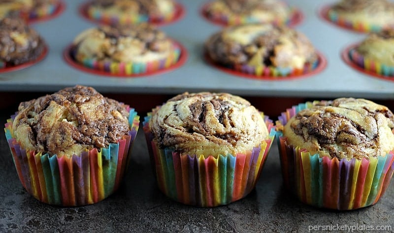 Nutella Muffins are a simple, moist muffin with a sour cream base, swirled with Nutella - you'll almost think you're eating a cupcake! | www.persnicketyplates.com #nutella #muffins #breakfast three nutella muffins lined up with muffin tray in background