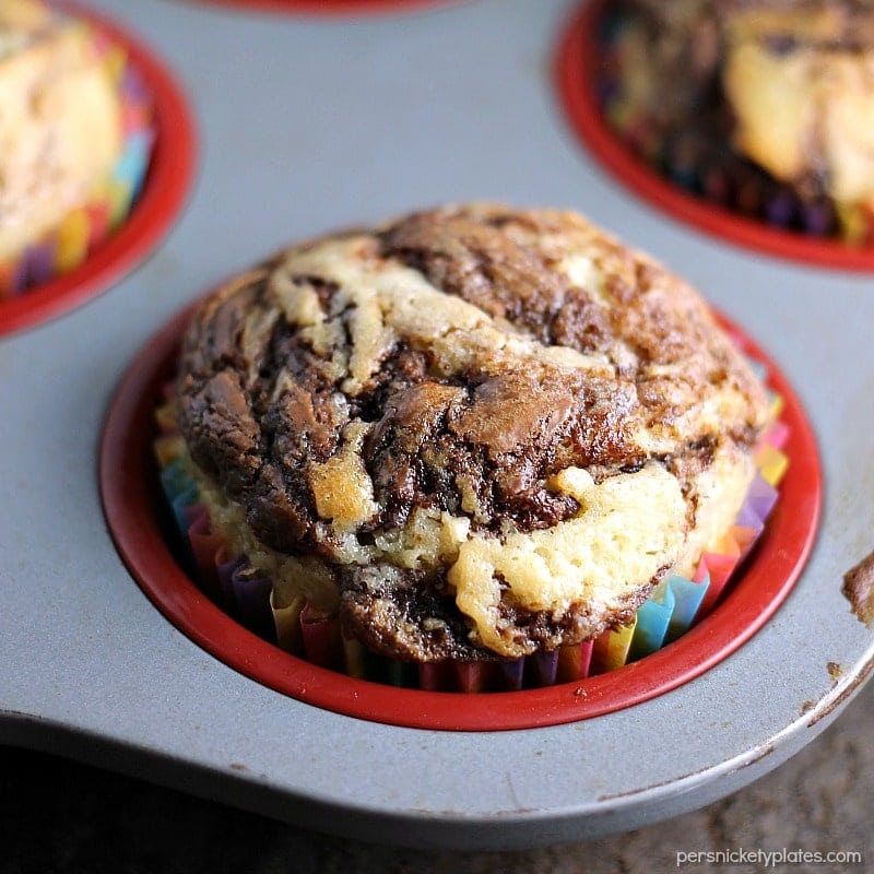 Nutella Muffins are a simple, moist muffin with a sour cream base, swirled with Nutella - you'll almost think you're eating a cupcake! | www.persnicketyplates.com #nutella #muffins #breakfast close up of nutella swirl muffin in muffin tin