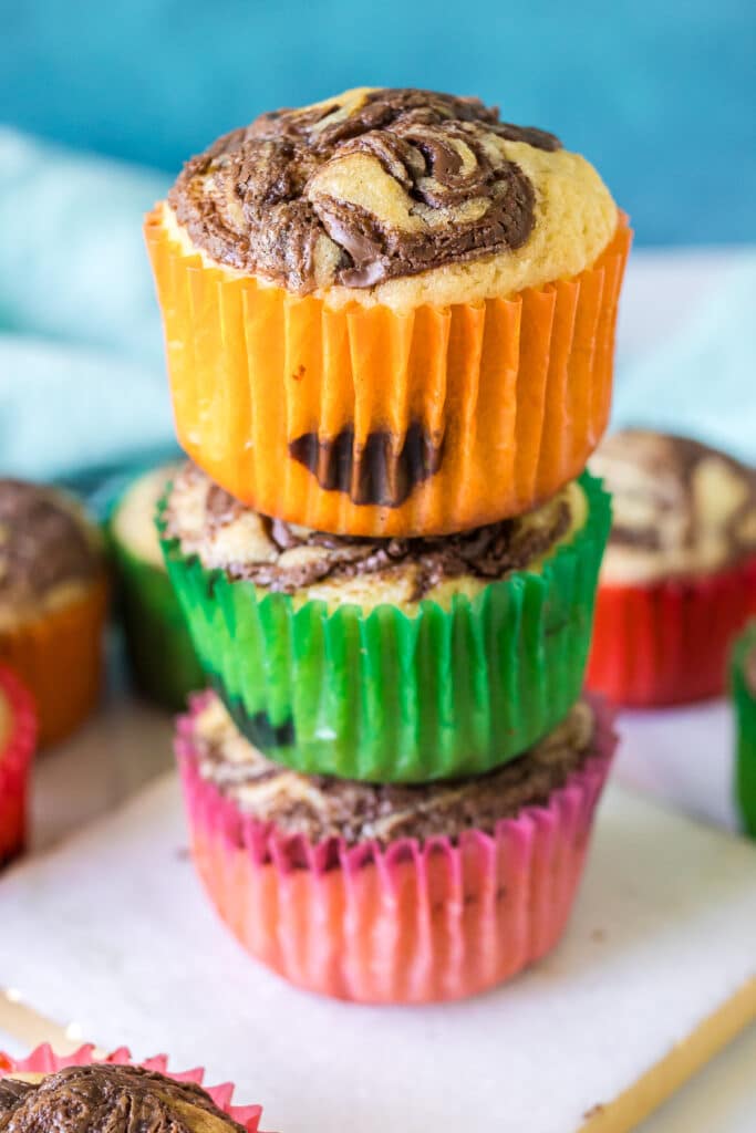 Nutella Muffins are a simple, moist muffin with a sour cream base, swirled with Nutella - you'll almost think you're eating a cupcake! | www.persnicketyplates.com #nutella #muffins #breakfast stack of 3 nutella muffins.