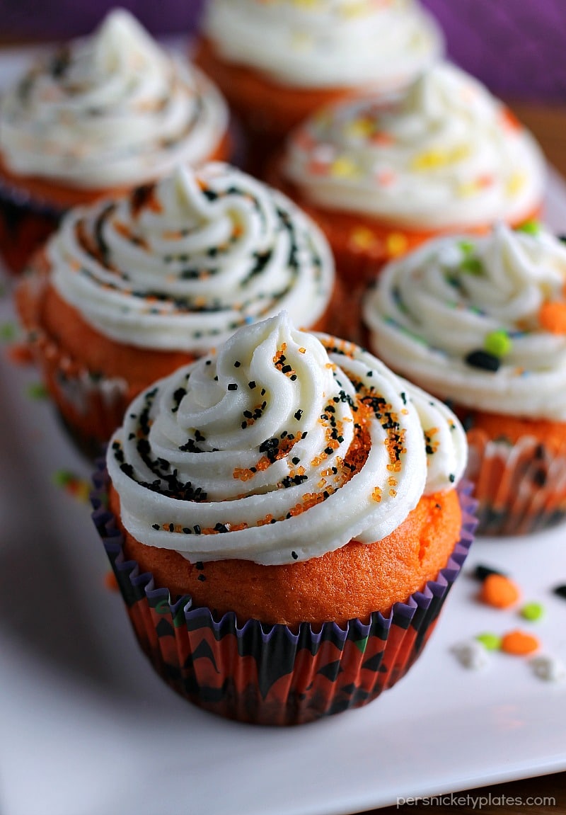 Brownie Bottom Halloween Cupcakes have a layer of dark chocolate brownie topped with orange cake batter and finished off with buttercream and sprinkles. They are the perfect mix of semi-homemade and "from scratch" to be easy but really fun and festive for your next Halloween party! | Persnickety Plates
