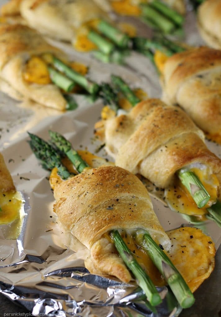 Cheesy Asparagus Puffs are a quick appetizer or side dish. Fresh asparagus wrapped up with provolone and cheddar cheeses and baked in a crescent roll - easy, cheesy, and delicious! | www.persnicketyplates.com #cheese #cheesy #appetizer #asparagus #vegetarian cheesy asparagus puffs on baking sheet straight from the oven