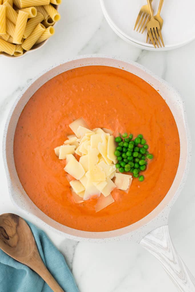 shaved parmesan and fresh basil in a pot of vodka sauce.