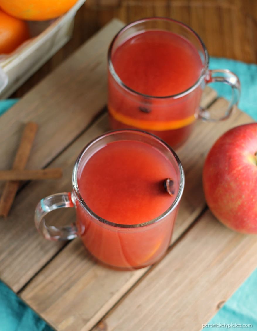 overhead shot of glass mugs of cider with cinnamon sticks.