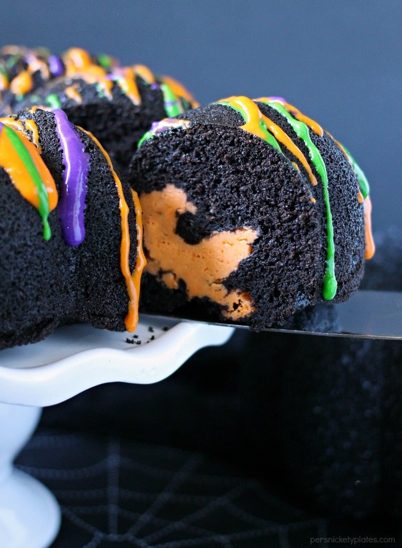Halloween Chocolate Tunnel Cake is a moist, from scratch, dark chocolate cake filled with a tunnel of orange cheesecake center and drizzled with a cream cheese frosting. Just the right amount of festive and spooky for your Halloween party! | www.persnicketyplates.com