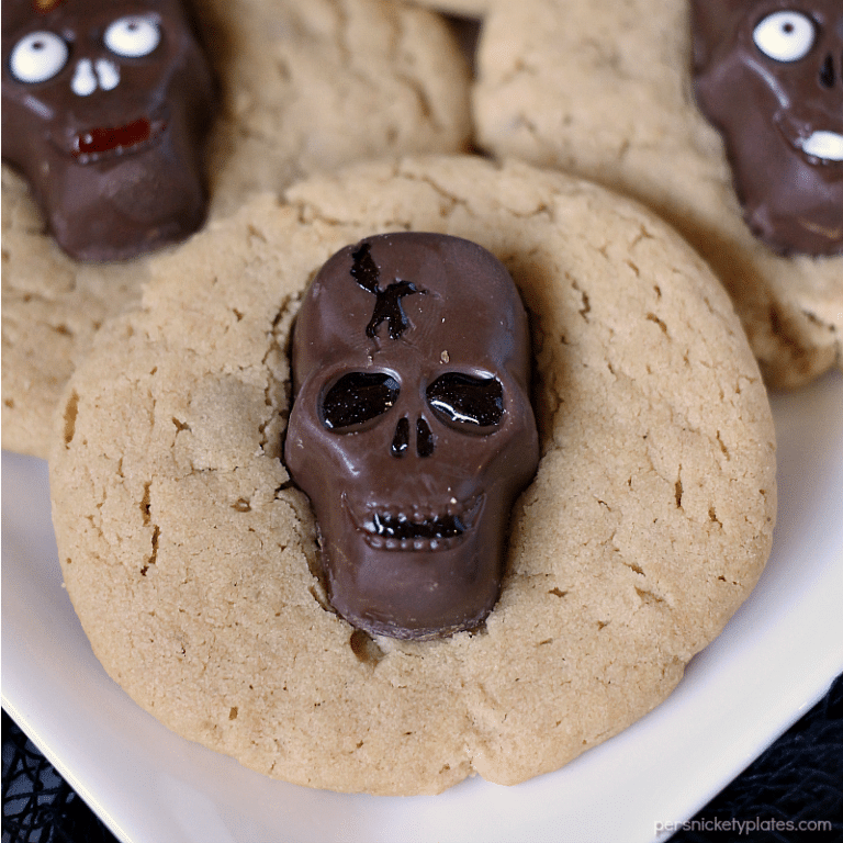Peanut Butter Butterfinger Skull Cookies start with a soft and chewy from scratch peanut butter cookie then are topped with a spooky, decorated Butterfinger Peanut Butter Skull Cup. Perfect for any Halloween party! | www.persnicketyplates.com