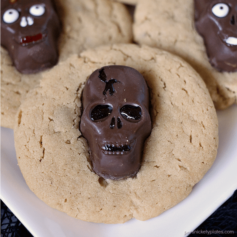 Peanut Butter Butterfinger Skull Cookies start with a soft and chewy from scratch peanut butter cookie then are topped with a spooky, decorated Butterfinger Peanut Butter Skull Cup. Perfect for any Halloween party! | www.persnicketyplates.com