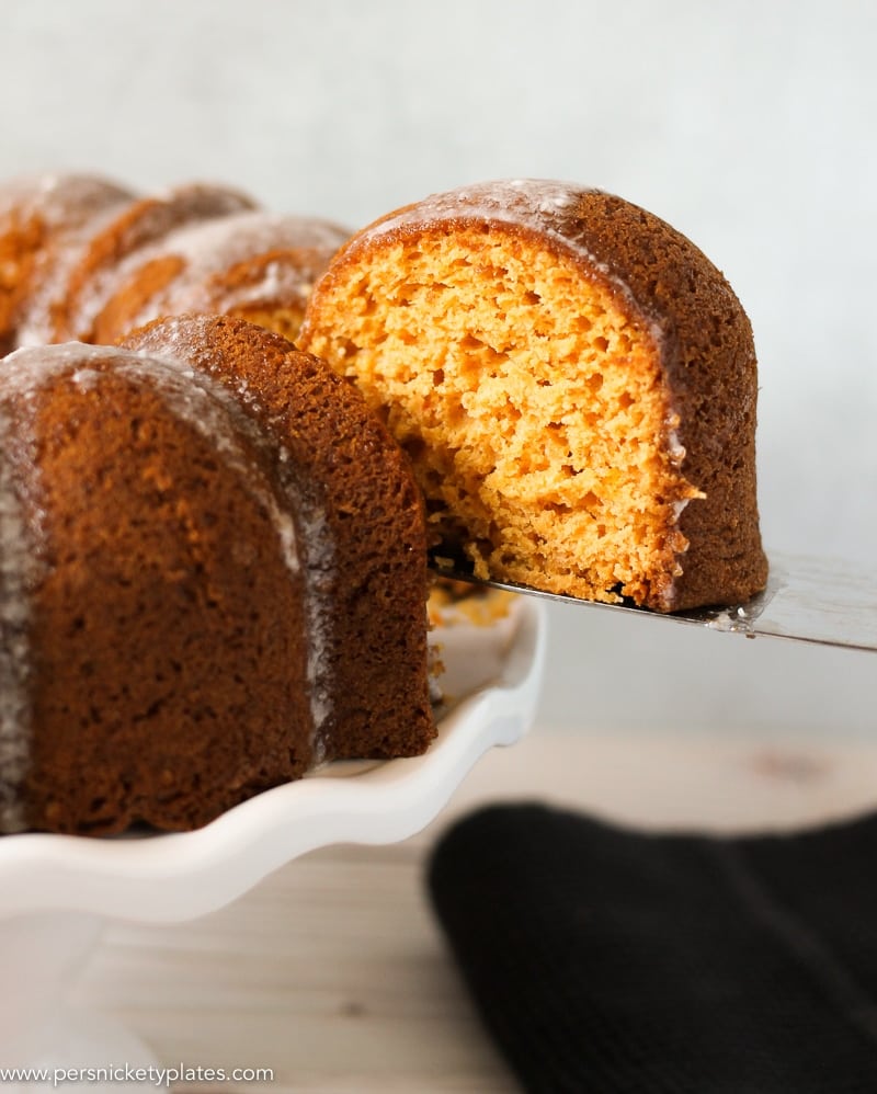 butterscotch bundt cake being sliced on a cake plate