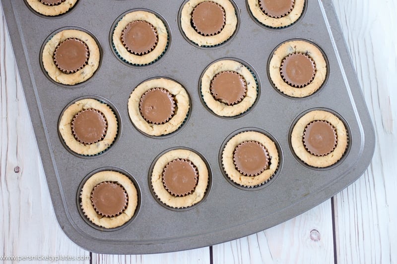Chocolate Chip Peanut Butter Cookie Cups are only two ingredients and are ready in just 20 minutes. Perfect for a last minute bake sale, class treat, or craving! | www.persnicketyplates.com #easydessert #cookie #cookiecups #semihomemade #dessert mini muffin pan filled with chocolate chip peanut butter cookie cups