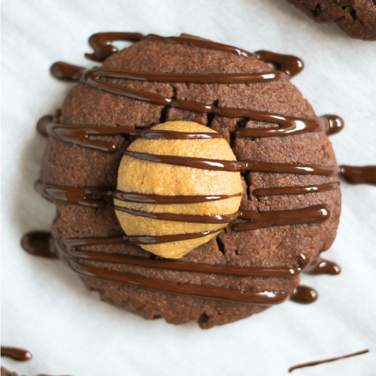 close up of chocolate cookie filled with peanut butter and drizzled with chocolate