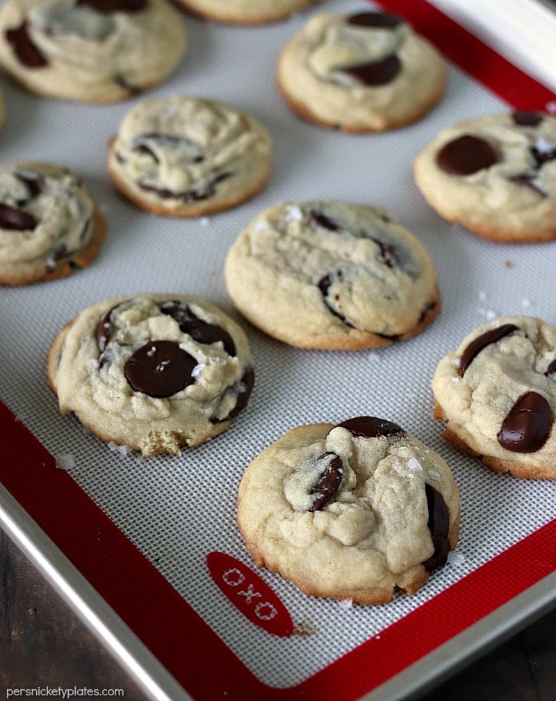 Once you try these thick, chewy, cake-like Salted Chocolate Chip Cookies, you're going to forget about all your other chocolate chip cookie recipes! | www.persnicketyplates.com baking sheet of Salted Chocolate Chip Cookies fresh out of the oven