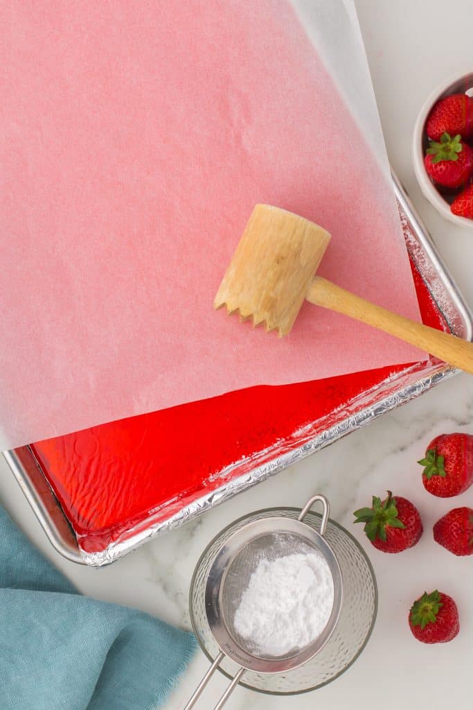 wooden mallet laying onto a baking sheet of hard candy.
