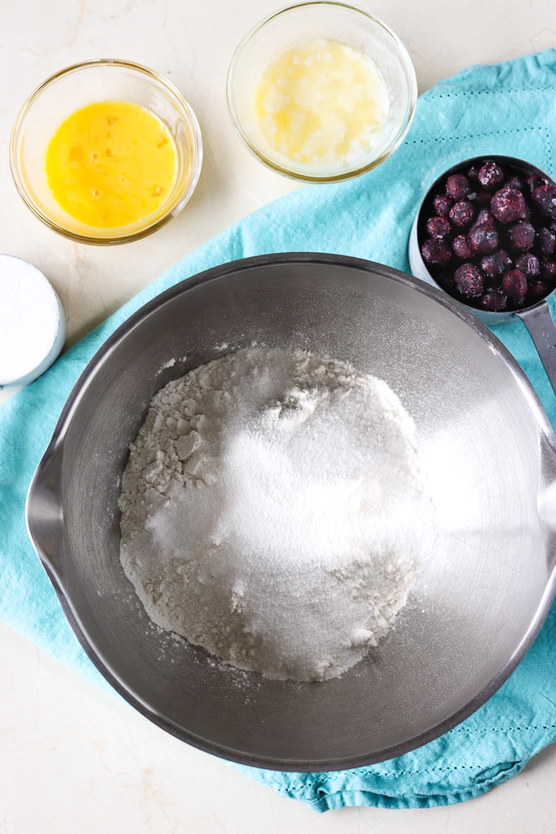 These Blueberry Muffins have a tender, buttermilk crumb, are full of blueberry flavor, and are topped with a crunchy sugary topping. Start your day off right with a batch of the best blueberry muffins! | www.persnicketyplates.com mixing bowl with ingredients for blueberry muffins