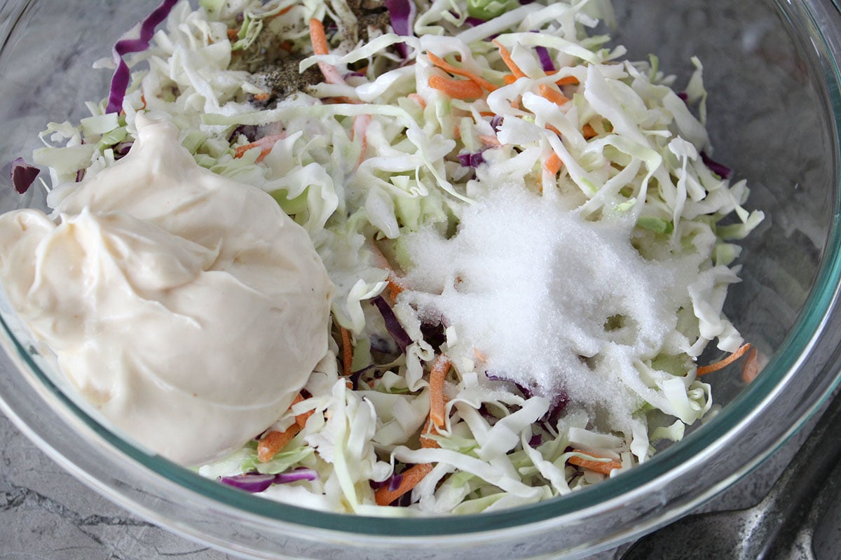 mixing bowl with shredded cabbage, sugar, and miracle whip
