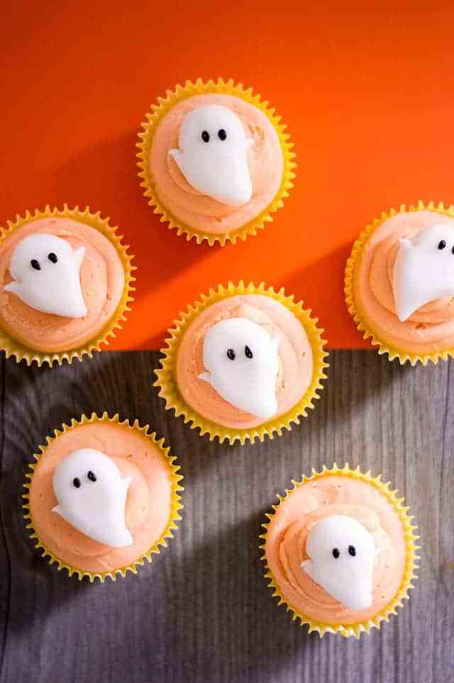 overhead shot of orange frosted cupcakes with ghosts on top