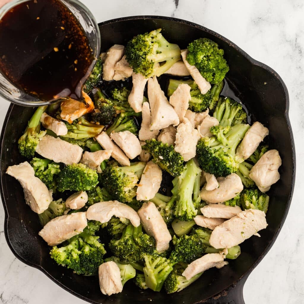 brown sauce pouring over a chicken broccoli skillet.