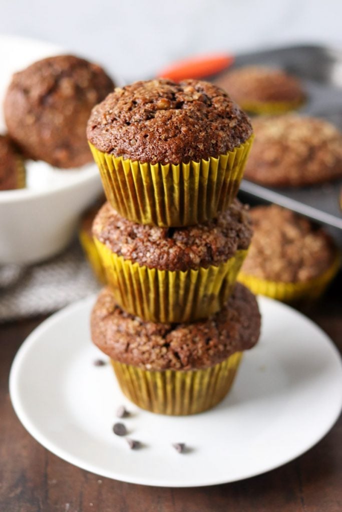 stack of 3 chocolate muffins in yellow wrappers.