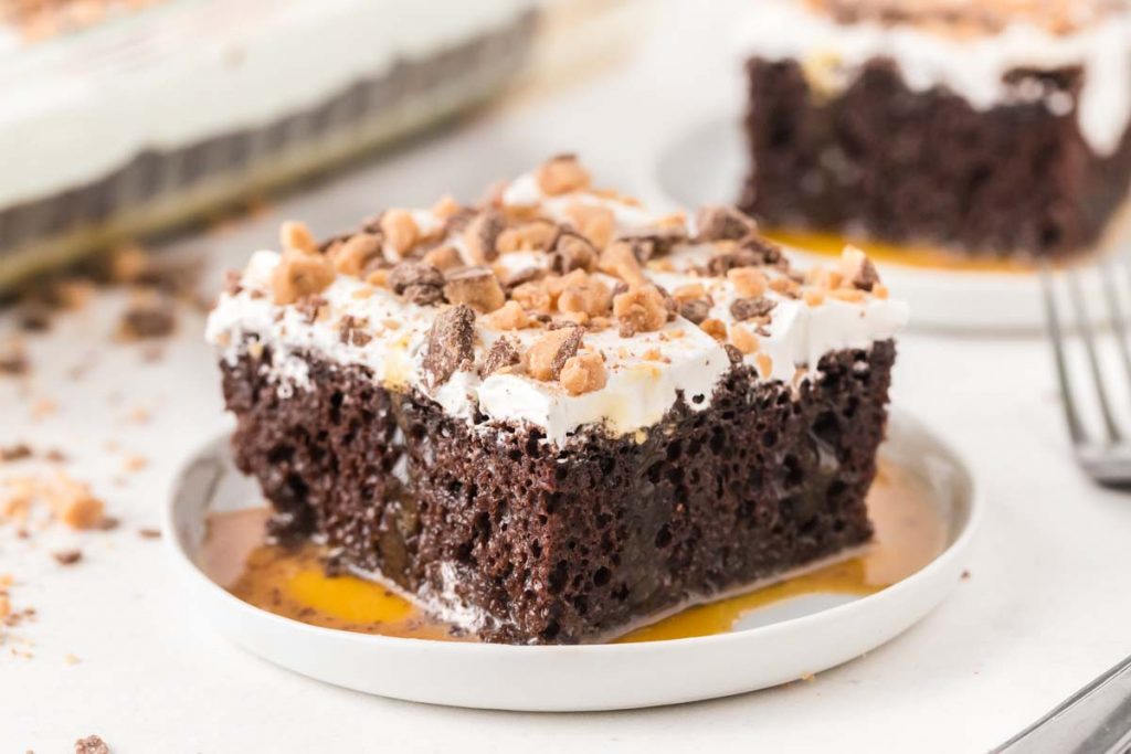 slice of chocolate cake sitting in caramel sauce on a white plate