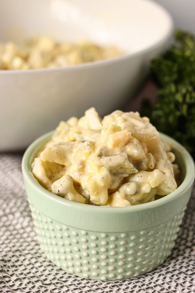 potato salad in light green dish in front of serving bowl
