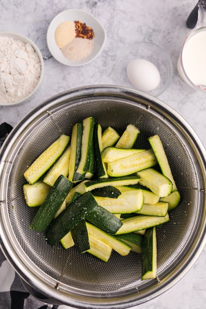 zucchini sticks in a colander.