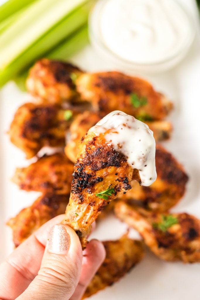 hand holding a chicken wing dipped in bleu cheese