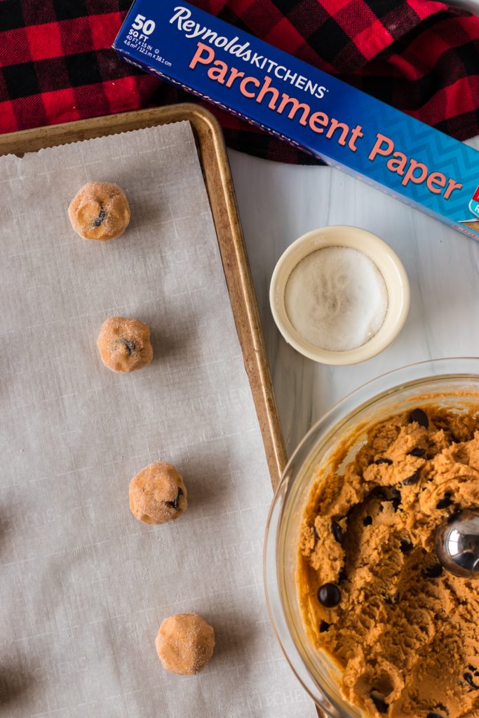 overhead shot of cookie dough balls on a baking sheet with reynolds parchment paper