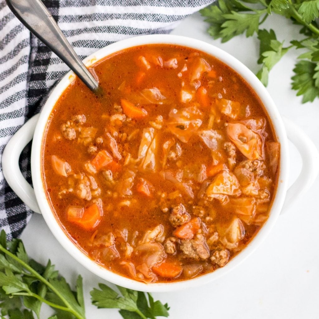 a bowl of cabbage roll soup with fresh parsley around it