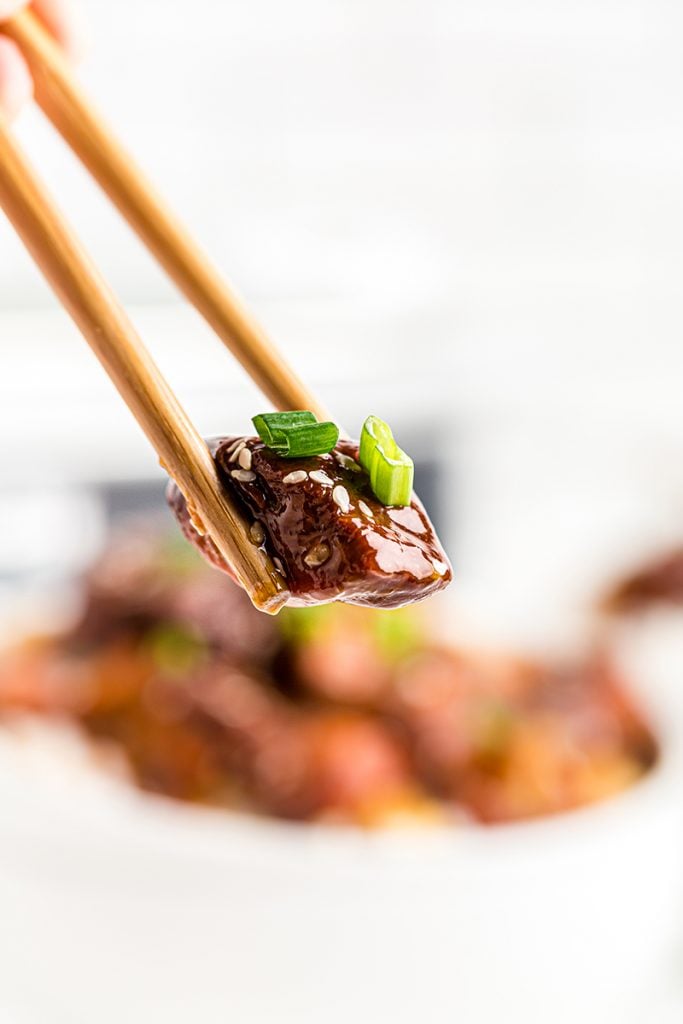 bite of crockpot sweet and sour chicken using chopsticks