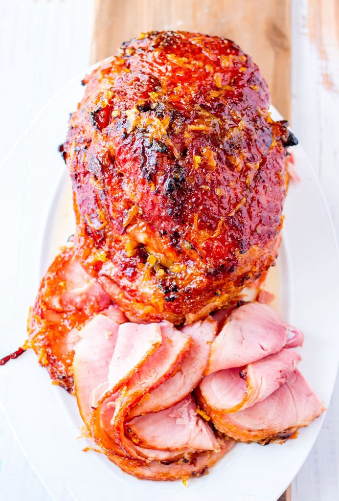 spiral sliced ham on a platter with slices in front of it