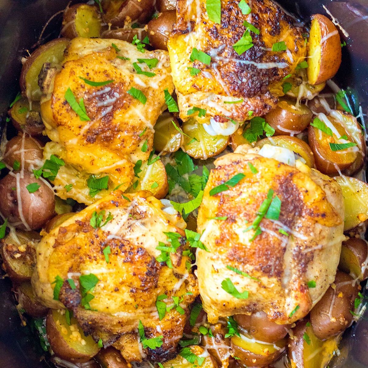 overhead shot of chicken thighs in slow cooker garnished with parsley