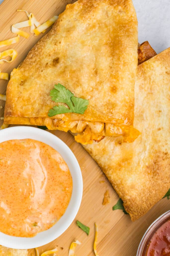 bowl of copycat taco bell quesadilla sauce next to a quesadilla triangle.