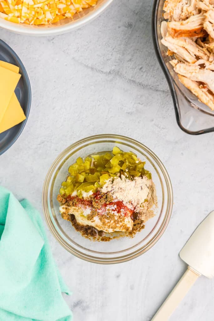 overhead shot of ingredients in a glass bowl to make spicy jalapeno sauce.