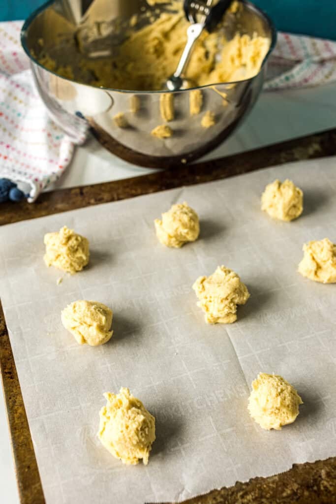 sugar cookie dough balls on a baking sheet.