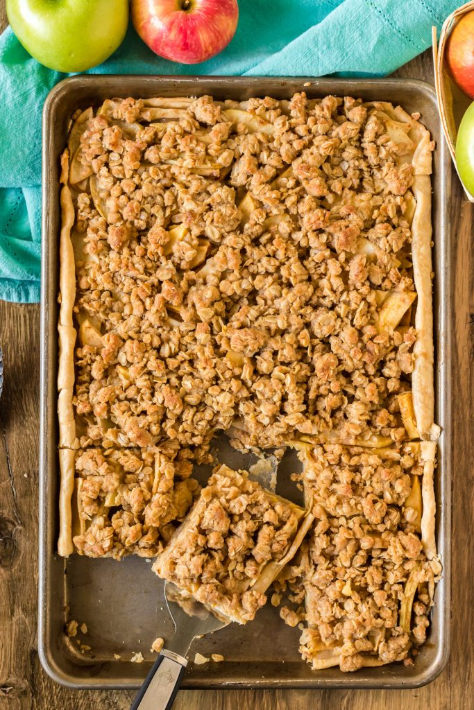 overhead shot of a slice of apple slab pie being removed from a baking sheet