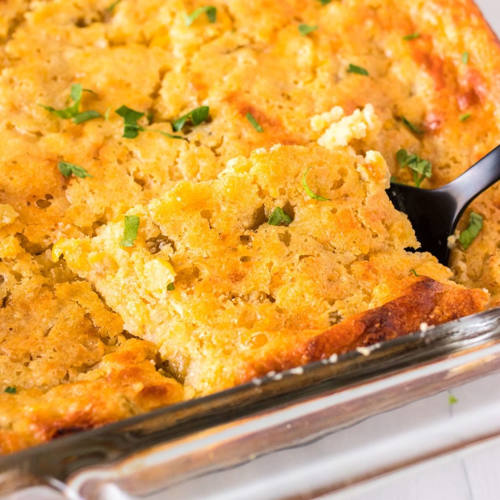 green chile corn casserole being lifted from a baking dish