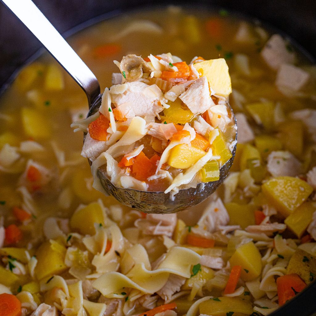 ladle scooping leftover turkey soup from the crockpot