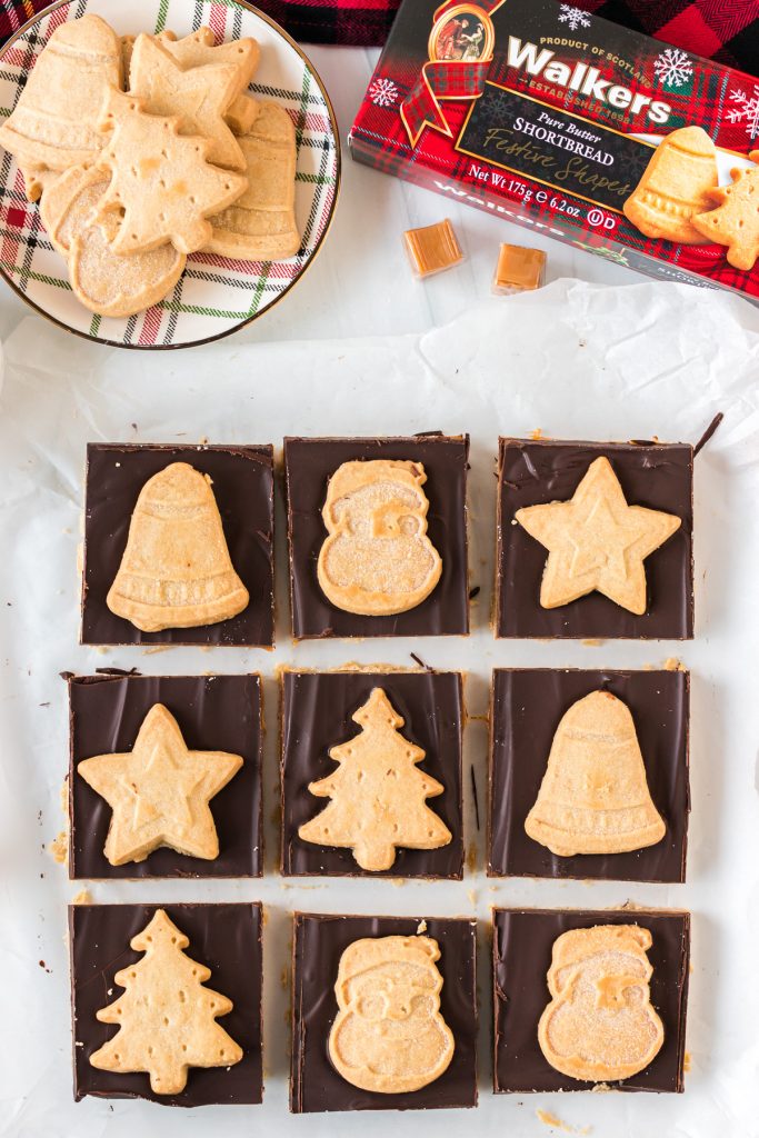 overhead shot of sliced millionaire bars topped with christmas shaped cookies