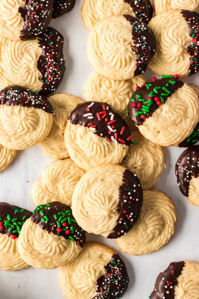 overhead shot of a pile of chocolate dipped butter cookies topped with christmas sprinkles