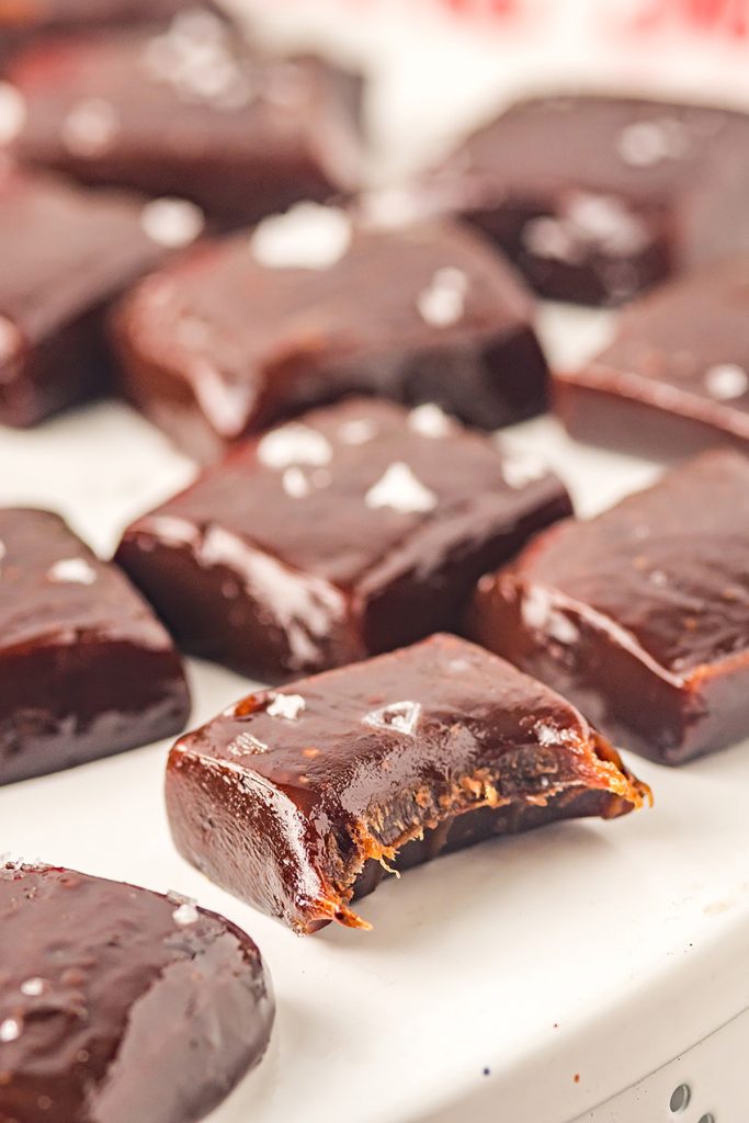 sea salt chocolate caramels on a white plate with a bite taken out of one